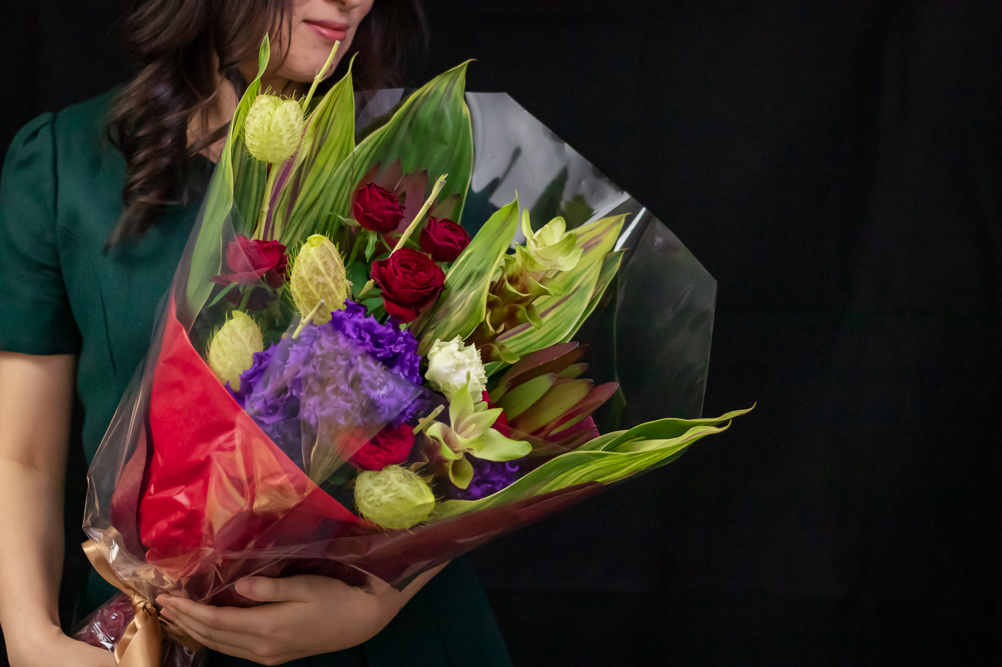 写真：大きく個性的な花束を抱き抱える女性　黒背景